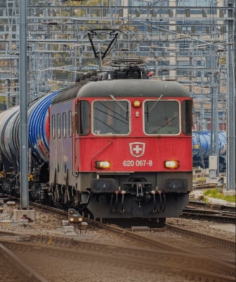 A locomotive hauling tank wagons through a rail yard